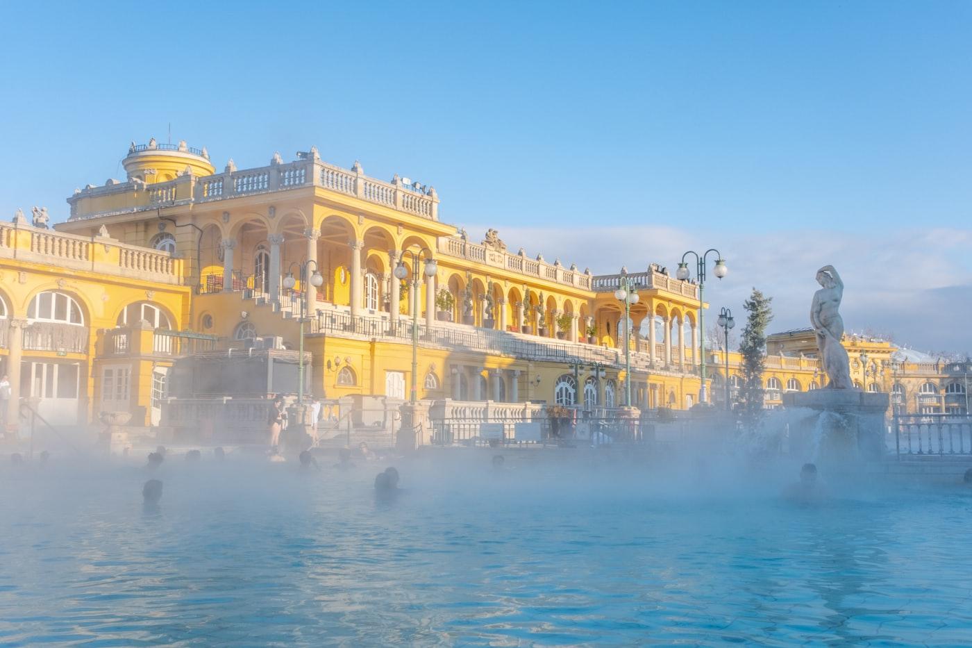 Steam rising from the outdoor thermal pool at the Széchenyi Baths, Budapest, with its yellow neo-baroque palace behind.